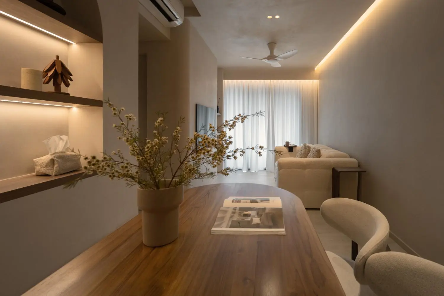 From dining table looking toward living — dried botanicals, sofa and sheer curtains