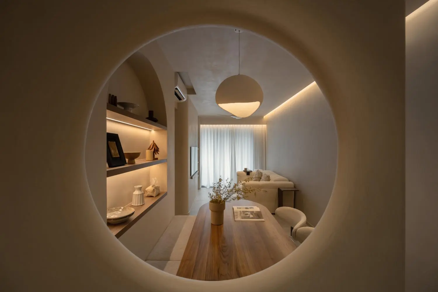Through the circular mirror cut-out — the living room framed as a composed view